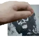 a hand is holding a picture of a skull on a piece of paper .