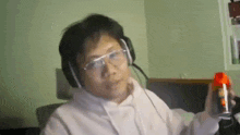 a man wearing headphones and glasses is holding a bottle of spray .