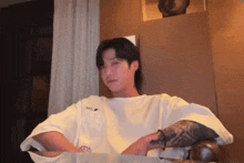 a man with a tattoo on his arm is sitting at a table with his arms crossed .