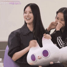 two girls are sitting next to each other and one is holding a stuffed animal