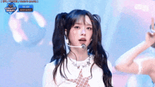 a girl with pigtails is singing into a microphone while wearing a white shirt .