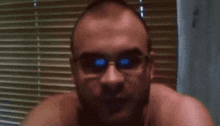 a man without a shirt is wearing a pair of blue sunglasses