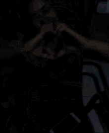a woman is making a heart shape with her hands while holding a cell phone .