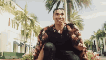 a man wearing a fur coat is sitting in front of a building