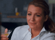 a woman in a white shirt is smiling while holding a martini glass