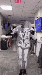 a person dancing in a hallway with a red exit sign above them