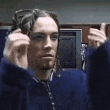 a man with dreadlocks is wearing a blue jacket and holding a pair of scissors .