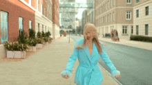 a woman in a blue jacket walking down a street