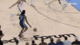a basketball player is dribbling the ball on a basketball court while another player tries to stop him .