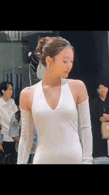 a woman in a white dress and gloves stands in front of a mirror