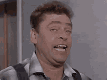 a man with a surprised look on his face is wearing suspenders .