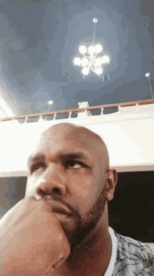 a man with a beard is looking up at a chandelier hanging from the ceiling