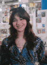 a woman wearing sunglasses and a blue shirt is smiling for the camera