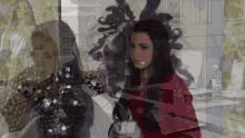 a woman in a red jacket is standing in front of a glass wall holding a cup .