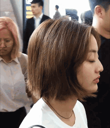 a woman with short brown hair is wearing a white shirt and necklace