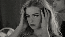 a black and white photo of a woman covering her ears with her hands