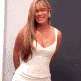 a woman in a white dress is smiling and looking at the camera