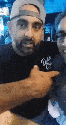 a man wearing a shirt that says daddy 's chill is pointing at another man