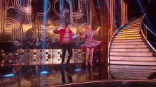 a man and woman are dancing on a stage in front of stairs .