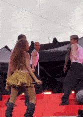 a woman in a gold skirt is dancing on a stage