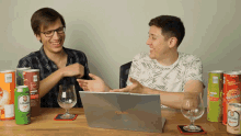 two men are sitting at a table with a asus laptop