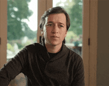 a man wearing a black sweater is looking at the camera
