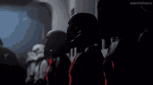 a group of stormtroopers are standing next to each other in a hallway .