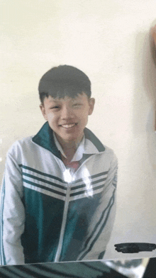 a young boy wearing a green and white jacket is smiling