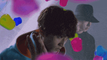 a man in a black hat is surrounded by colorful balloons