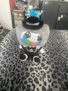 a stuffed tv with a top hat is sitting on a bed
