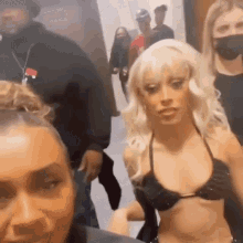 a group of women are posing for a picture in a room . one of the women is wearing a black bikini top .