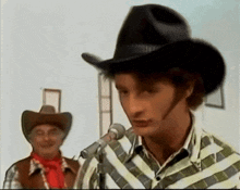 a man wearing a cowboy hat is speaking into a microphone