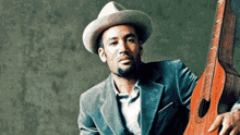a man in a hat is holding a guitar in his hand