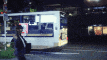 a woman walking in front of a bus that has the number 012434 on it