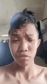 a young man without a shirt making a funny face
