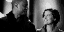 a black and white photo of a man and a woman looking at each other and smiling .