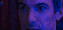 a close up of a man 's eyes in a dark room with blue lights behind him .