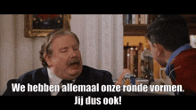 a man in a suit and tie is talking to another man with the words wij dus ook written on the screen