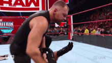 a wrestler is kneeling down in a wrestling ring while a crowd watches .