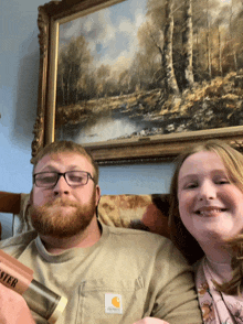 a man wearing a carhartt shirt sits next to a young girl