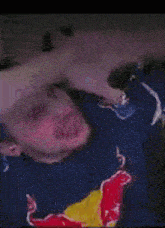 a man wearing a red bull shirt is laying down with his head down
