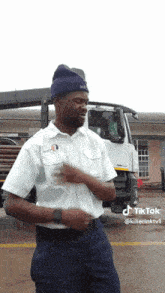 a man in a white shirt and blue pants is dancing in front of a truck and a building