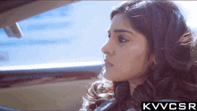 a woman is sitting in a car with the letters kvvcsr behind her