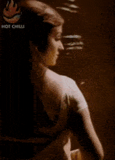 a woman in a white dress is standing in a dark room and looking at the camera .