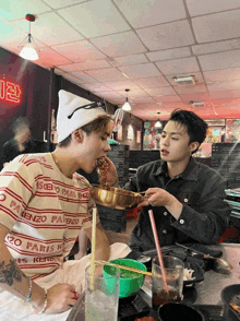 a man wearing a shirt that says ' enzo paris ' on it is eating from a bowl