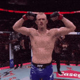 a shirtless ufc fighter flexes his muscles in front of a casey sign