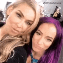 two women with purple hair are posing for a selfie together .