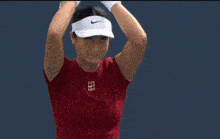 a woman in a red shirt is holding a tennis racquet with her mouth open .