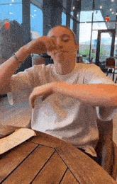 a woman in a white shirt is sitting at a table with her hands on her face
