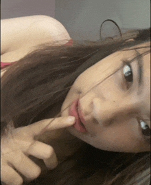 a woman with long hair is laying down with her finger on her lips